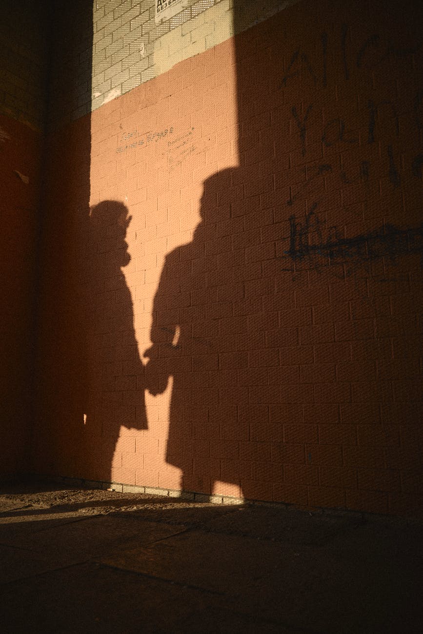 shadows of people casted on brick wall of derelict building